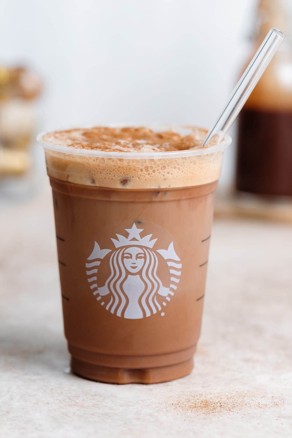Chocolate shaken espresso with ice and a glass straw in a plastic Starbucks cup.