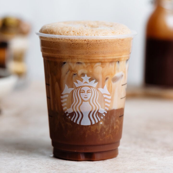 Frothy shaken espresso in a plastic Starbucks cup with milk mixing with the coffee.