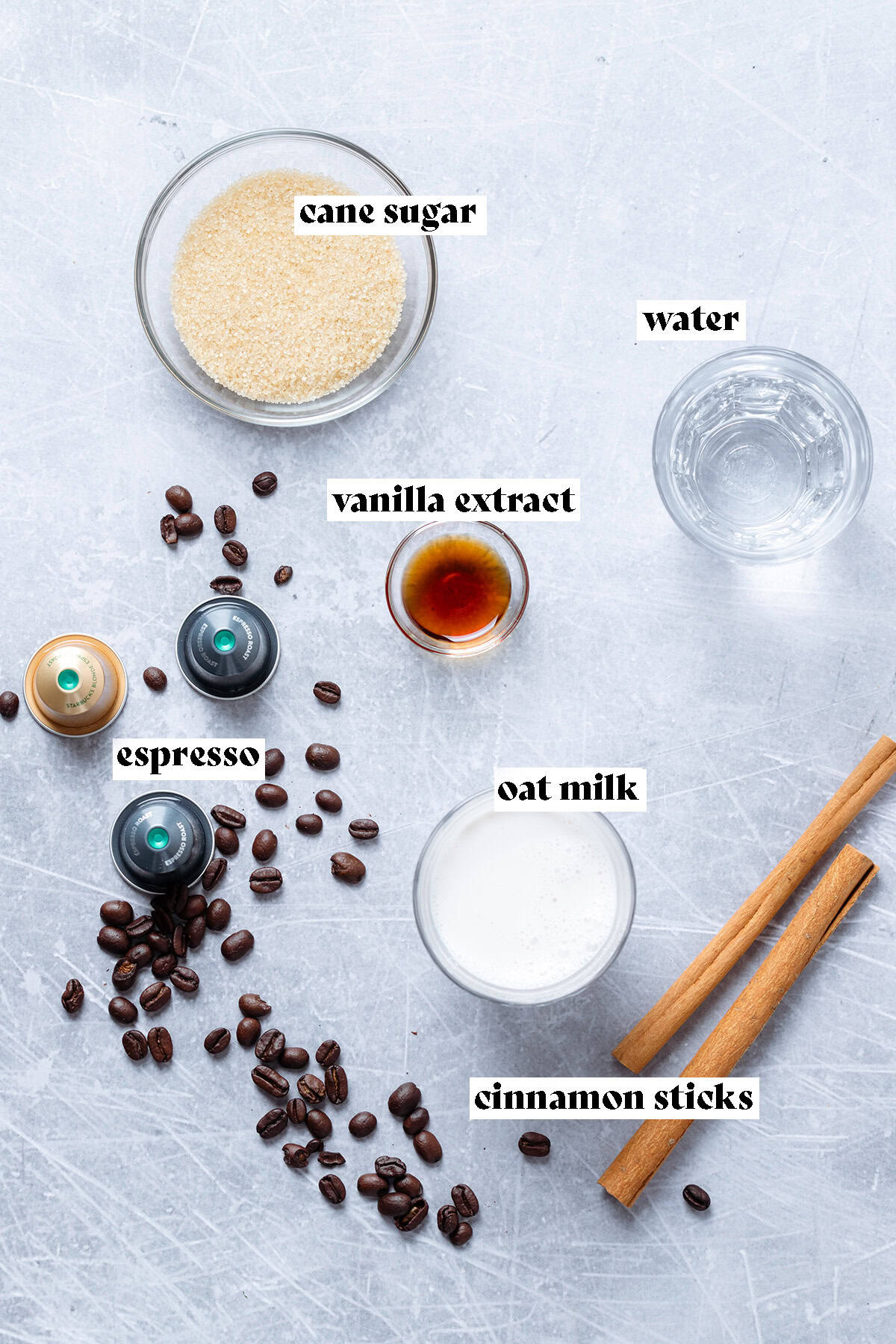 Ingredients for iced cinnamon latte like cane sugar, cinnamon sticks, and coffee beans.