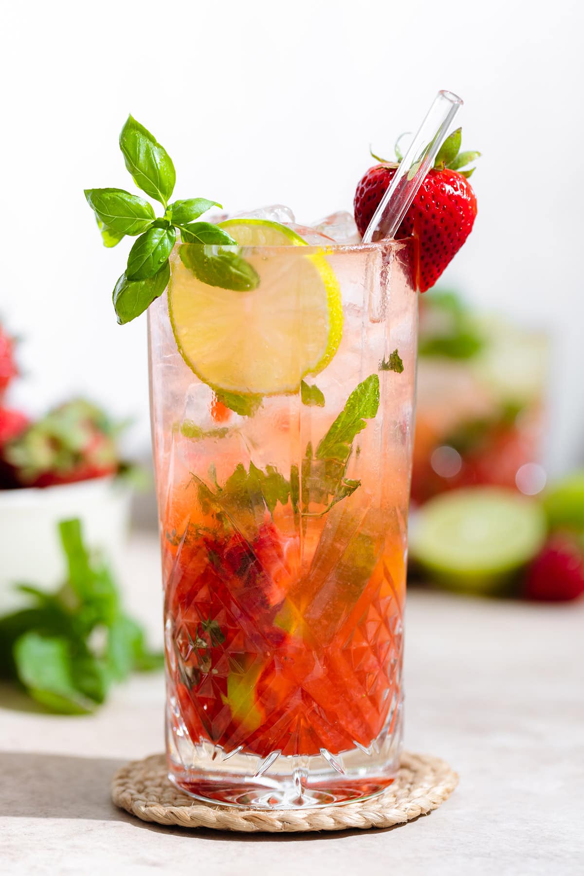 Strawberry basil mojito in a tall glass garnished with fresh basil, lime slice, and a strawberry.