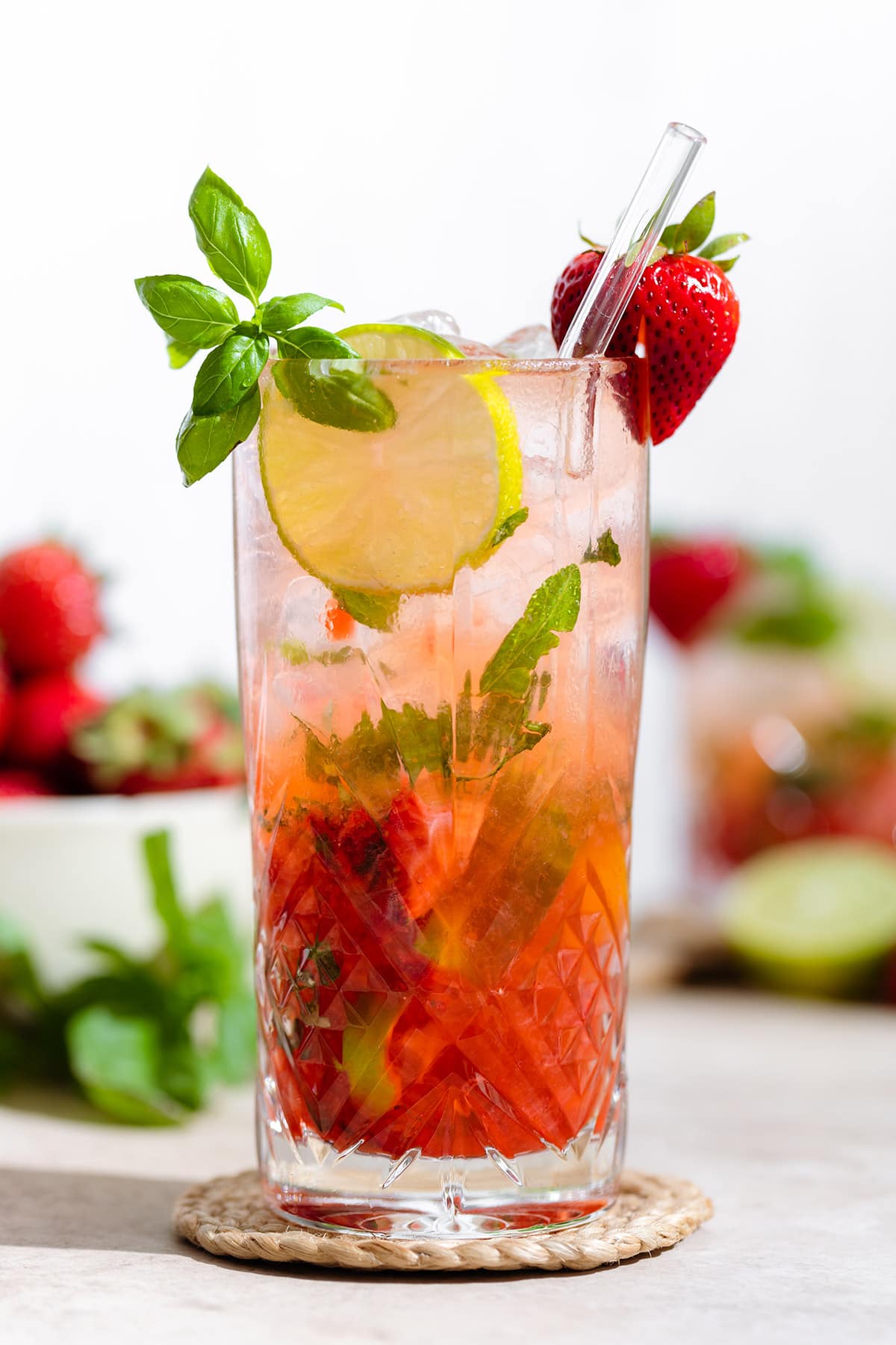 Strawberry basil mojito in a tall glass garnished with fresh basil, lime slice, and a strawberry.