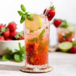 Strawberry basil mojito in a tall glass garnished with fresh basil, lime slice, and a strawberry.