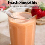 Peach colored smoothie in a tall glass with a glass straw and garnished with a fresh strawberry on the rim.