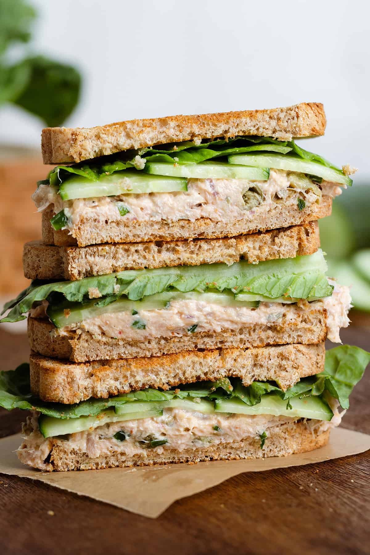 Tuna Cucumber Sandwiches stacked on a dark wooden cutting board.