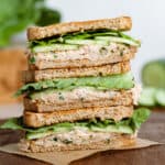 Tuna Cucumber Sandwiches stacked on a dark wooden cutting board.