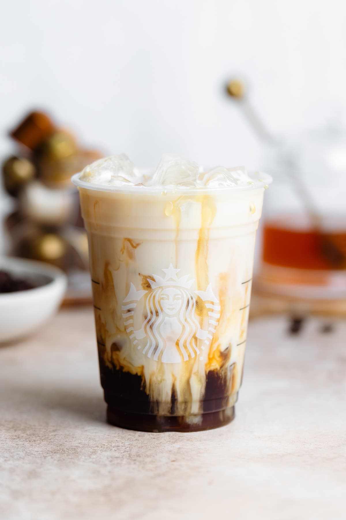 Almond milk slowly mixing into iced espresso in a plastic Starbucks cup.