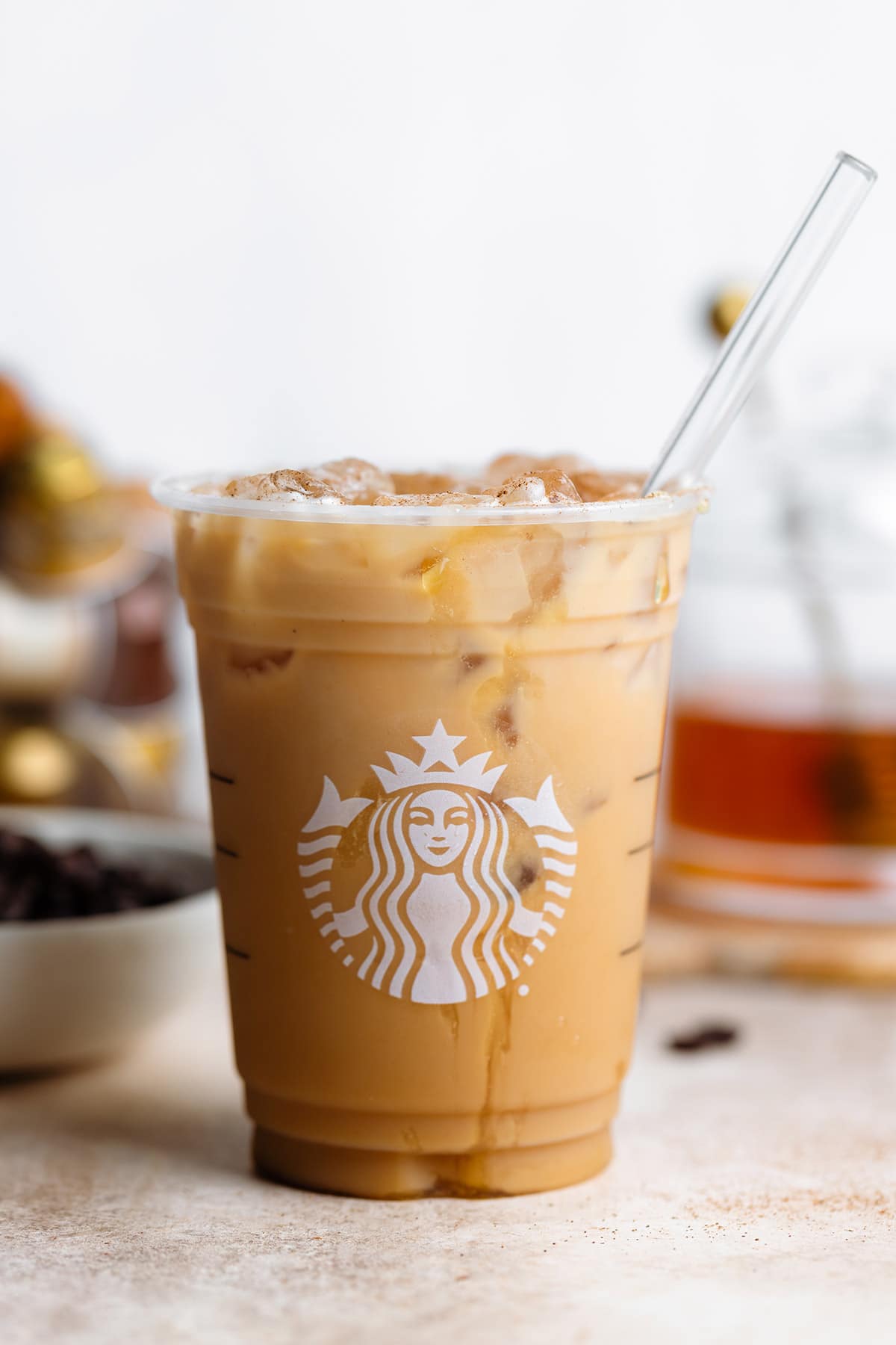 Iced coffee in a plastic Starbucks cup with a honey drizzle and a glass straw.