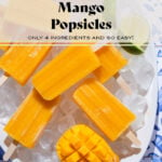 Bright orange mango popsicles on a white serving plate with ice and lime slices.
