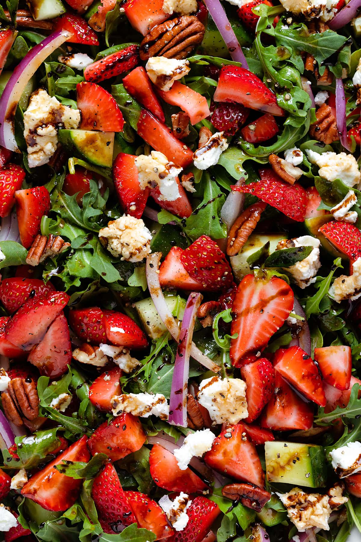 A close up of strawberry goat cheese salad with balsamic glaze drizzled over it.