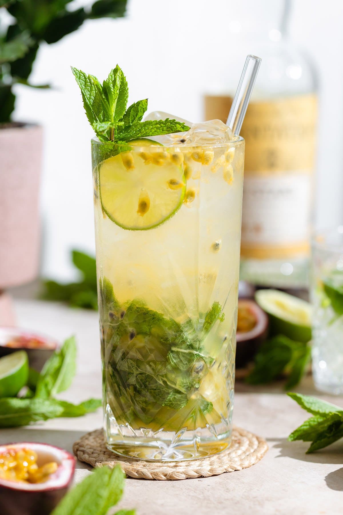 Passion fruit mojito in a tall glass with a glass straw garnished with fresh mint, lime, and passion fruit.