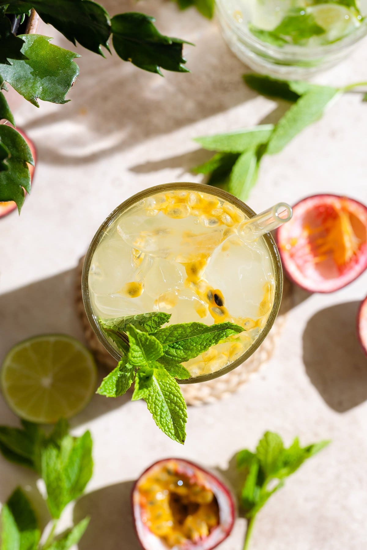 Passion fruit mojito in a tall glass shot from above with a glass straw garnished with fresh mint, lime, and passion fruit.