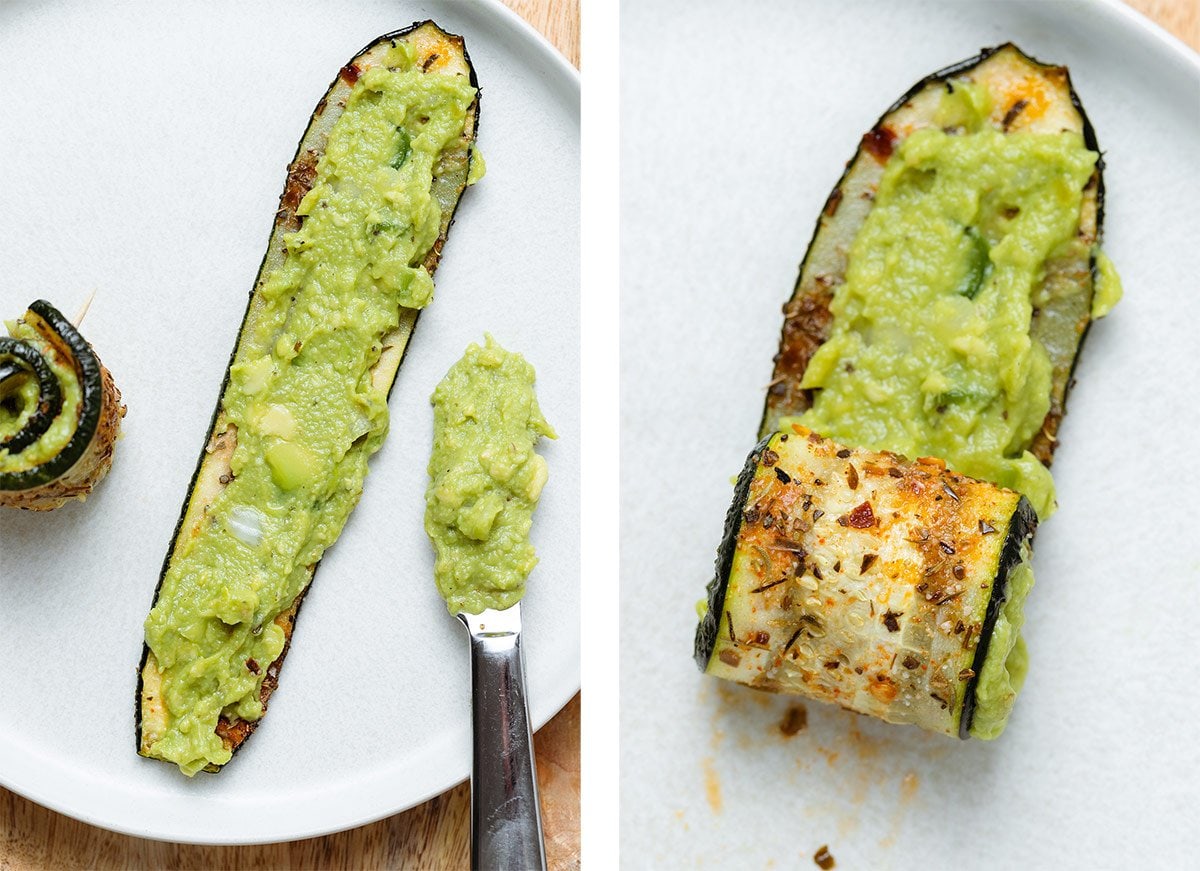 A roasted slice of zucchini being spread with guacamole and rolled up.
