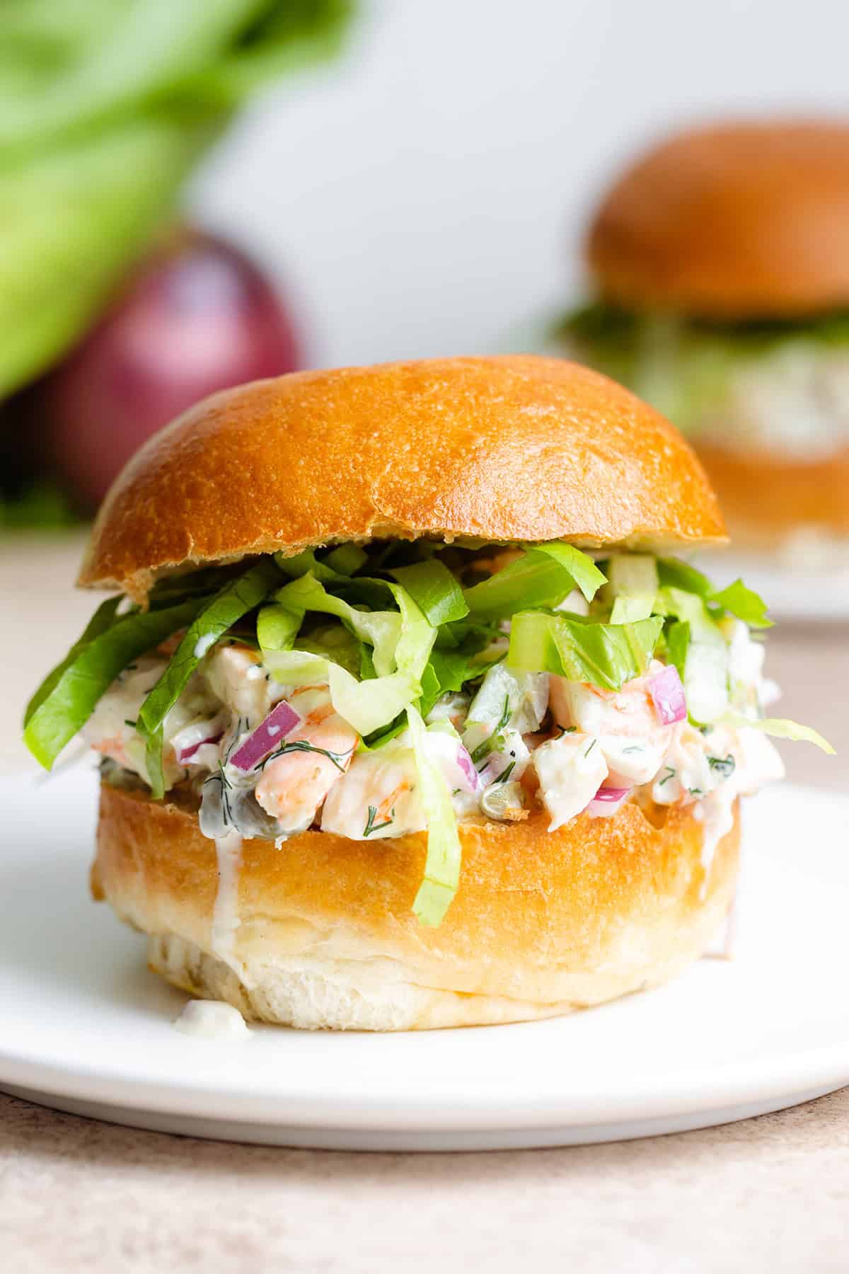 A toasted brioche bun with creamy shrimp salad and shredded romaine lettuce.