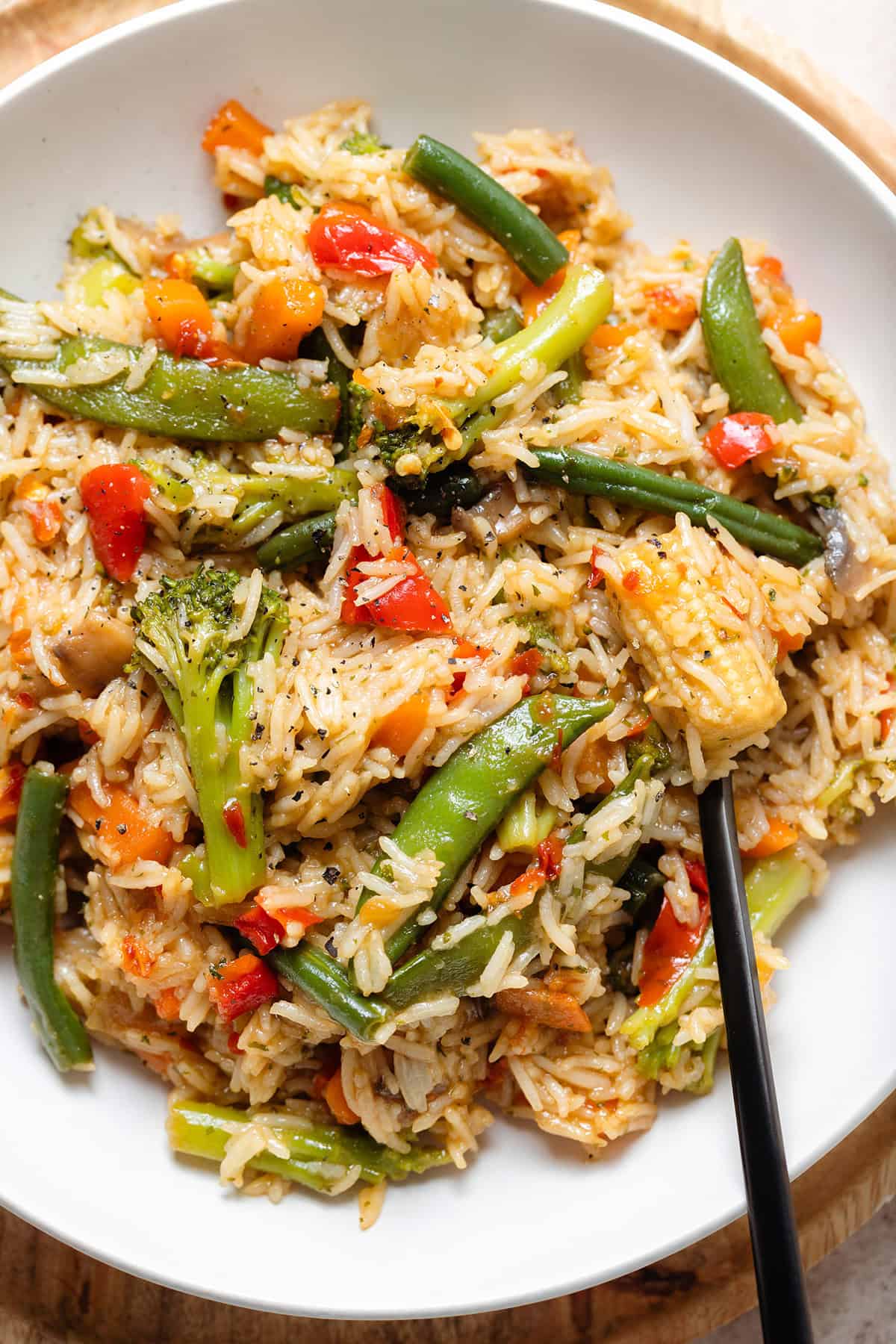 Stir fry with mixed thai style frozen vegetables in a white low bowl with a black fork on the right.