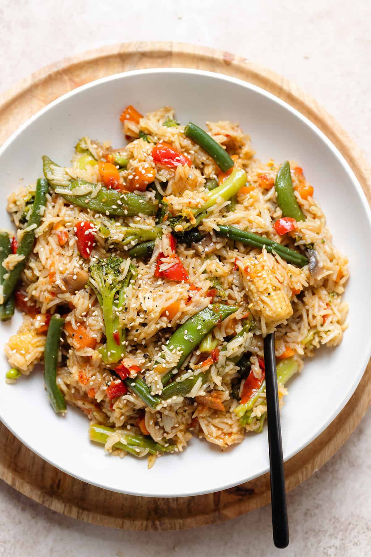 Stir fry with mixed thai style frozen vegetables in a white low bowl with a black fork on the right.