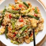 Stir fry with mixed thai style frozen vegetables in a white low bowl with a black fork on the right.