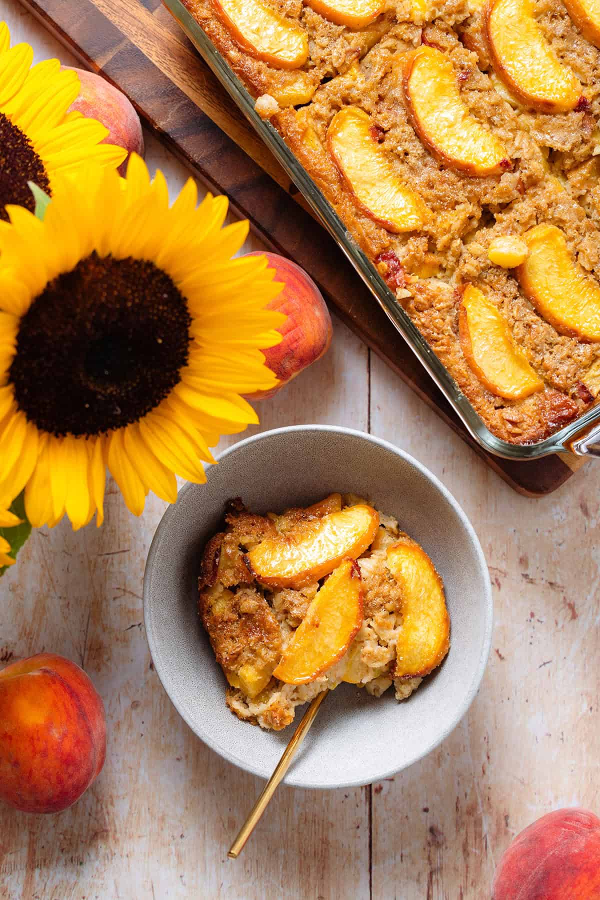 Peach baked oatmeal in a grey bowl topped with peaches and more baked oatmeal on the right.