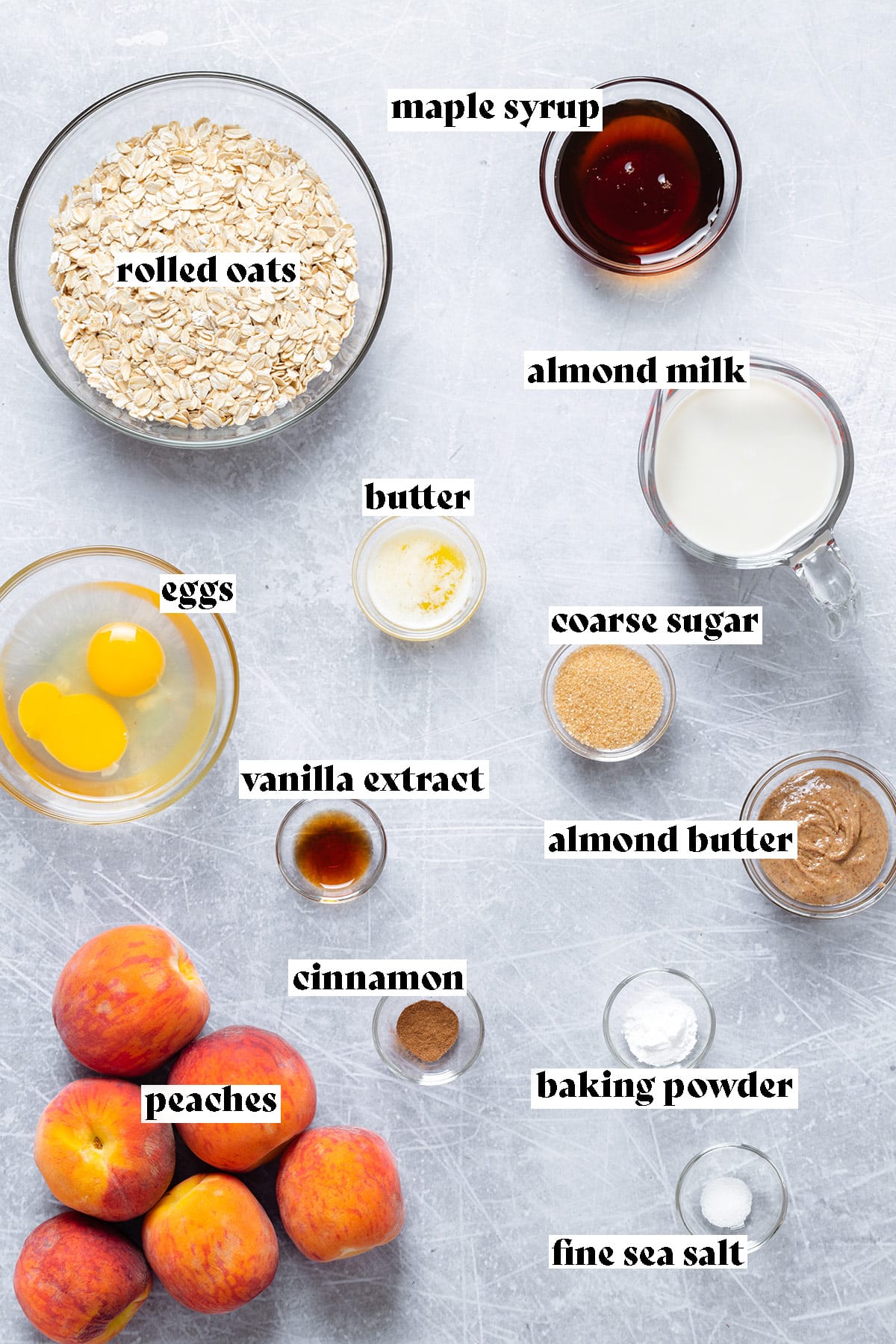 Ingredients for a peach baked oatmeal like oats, peaches, and eggs on a grey background.