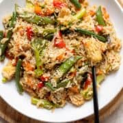Stir fry with mixed thai style frozen vegetables in a white low bowl with a black fork on the right.