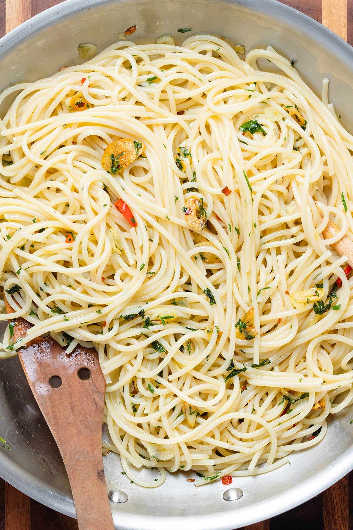Spaghetti with sauteed garlic, parsley, and chili peppers in a large skillet.