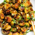 Charred saucy brussels sprouts topped with chopped fresh parsley.