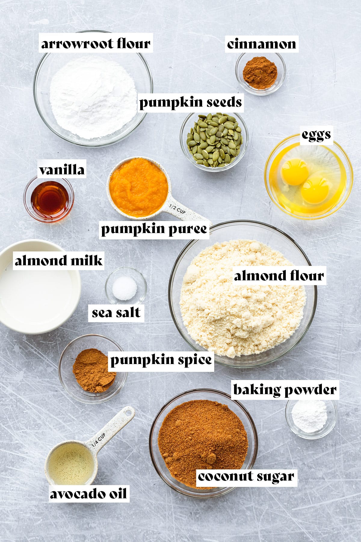 Almond flour, arrowroot flour, pumpkin puree, coconut sugar, and other ingredients on a grey background.