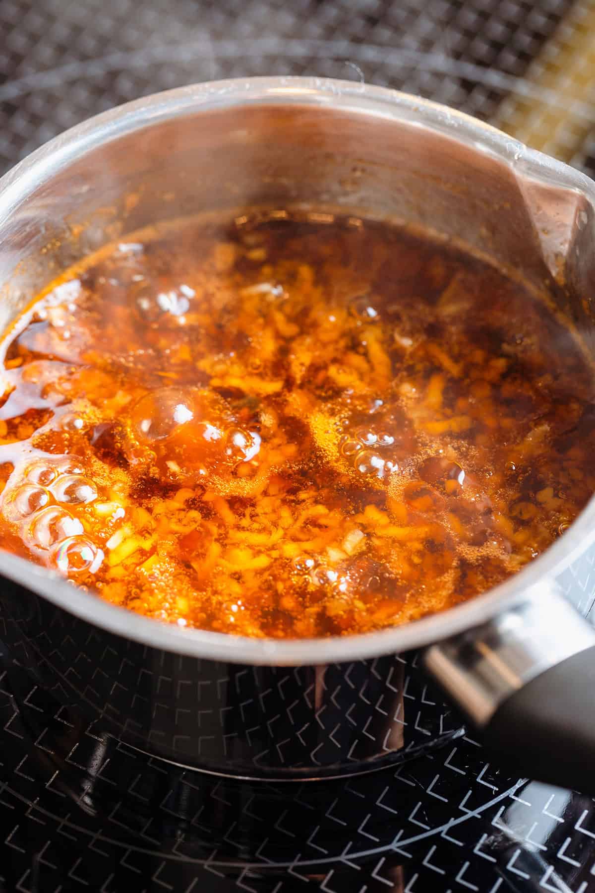 Golden soy glaze simmering in a small saucepan on the stove.