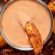 A small dipping bowl with house sauce and one fry dipped into it.