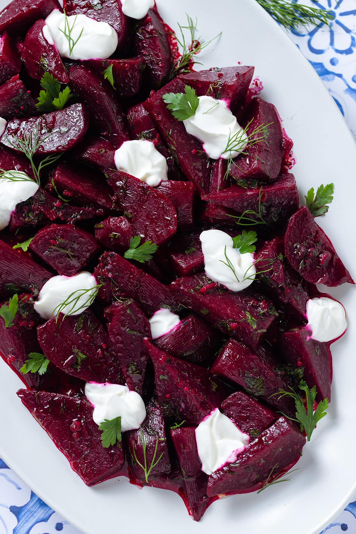 Beet salad with dollops of Greek yogurt and fresh herbs on a white serving platter.