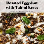 Halved roasted eggplant with spices, tahini sauce, herbs, and pine nuts.