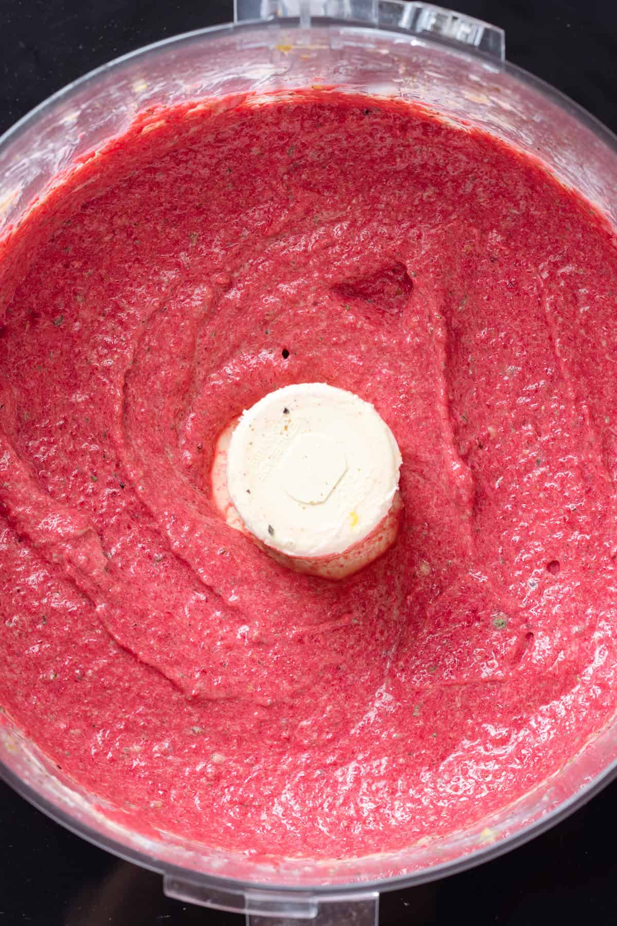 Bright pink beet dip in a food processor.