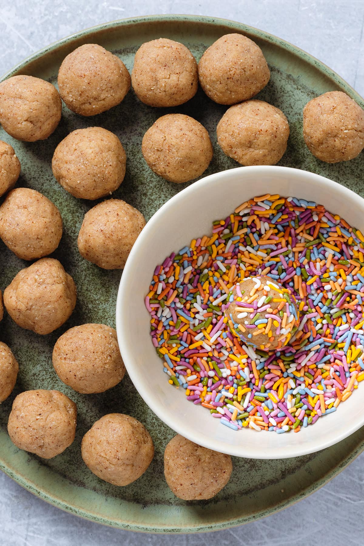 Birthday cake protein balls being covered with colorful sprinkles.