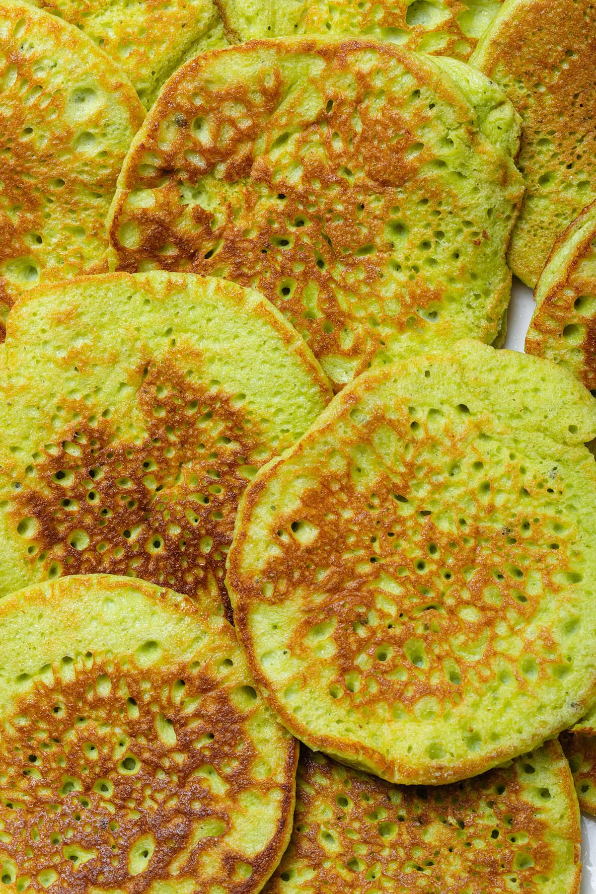 Bright green matcha pancakes laid out on a white plate.