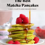 A stack of green matcha pancakes with fresh raspberries being drizzled with maple syrup on a white plate.
