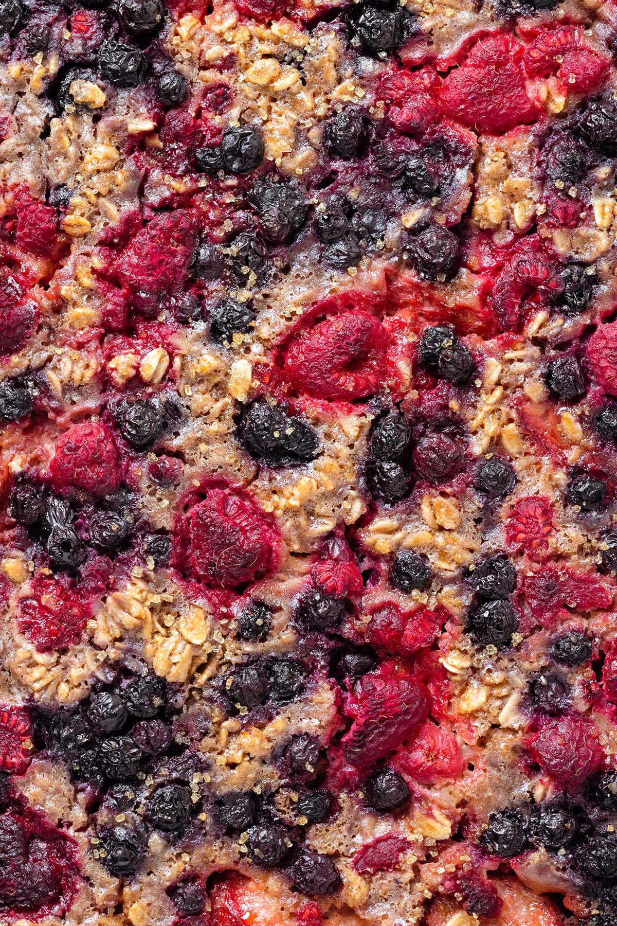Baked oatmeal with mixed berries showing the crispy exterior with caramelized berries.