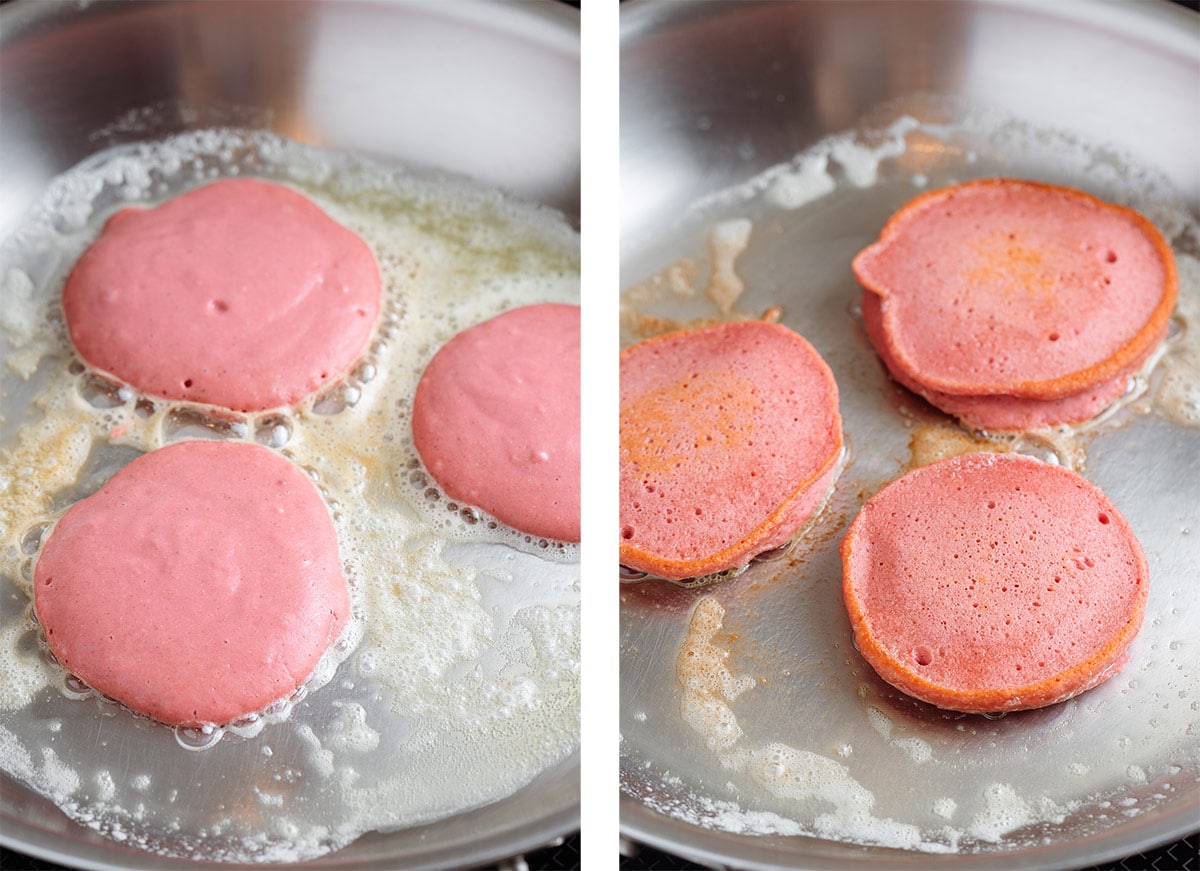 Pink pancakes cooking with butter in a large stainless steel pan.