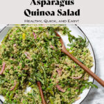 Quinoa salad with arugula, asparagus, and peas on a large serving platter with wooden spoons inserted in it.