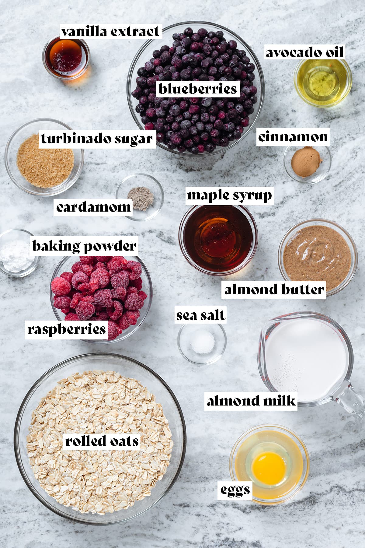 Ingredients for blueberry baked oatmeal like berries, oats, milk, and eggs on a stone background.