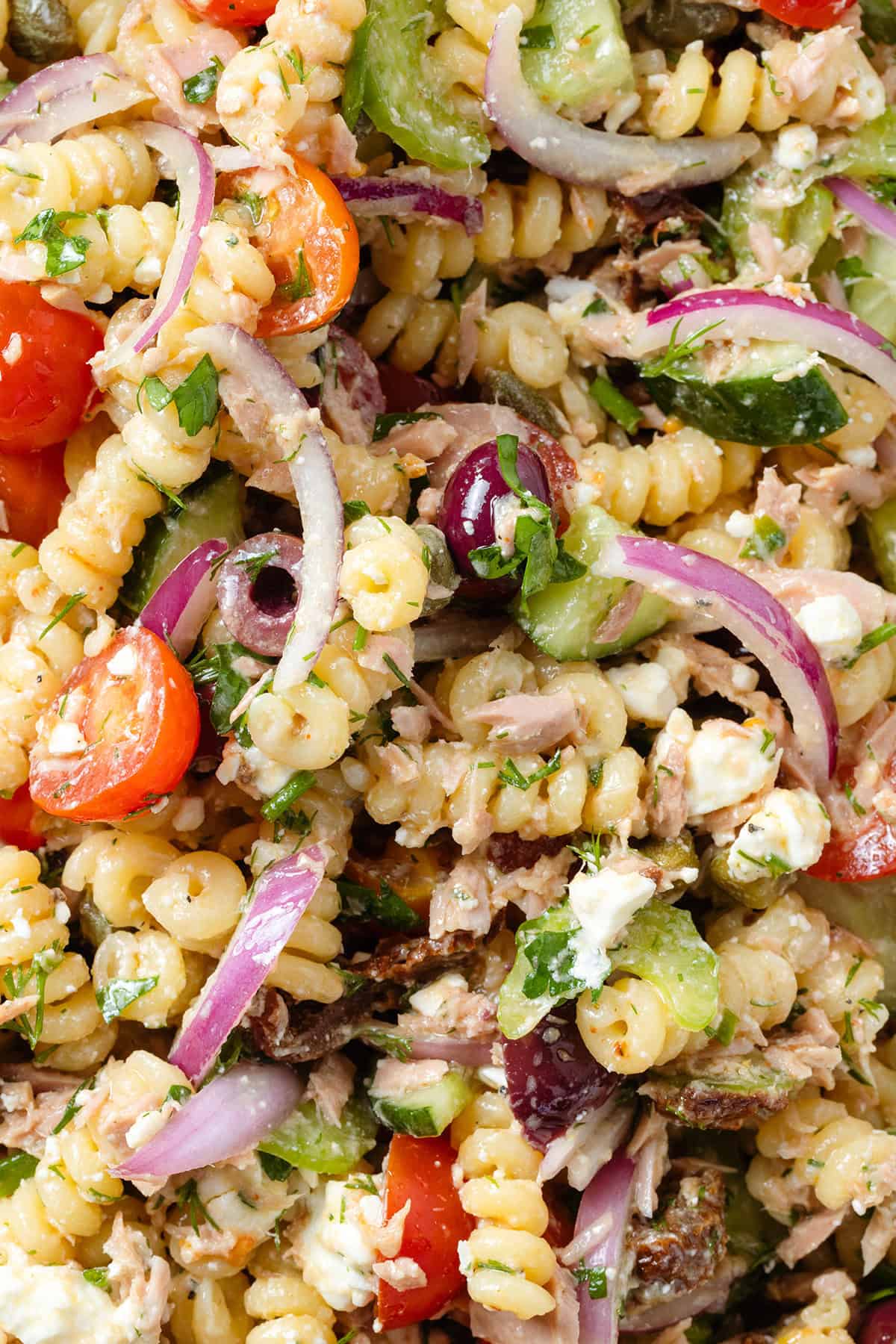 Close up of pasta salad with tuna, veggies, feta, and olives.