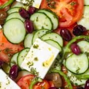 Layered Greek Salad with light herb vinaigrette drizzled over it.