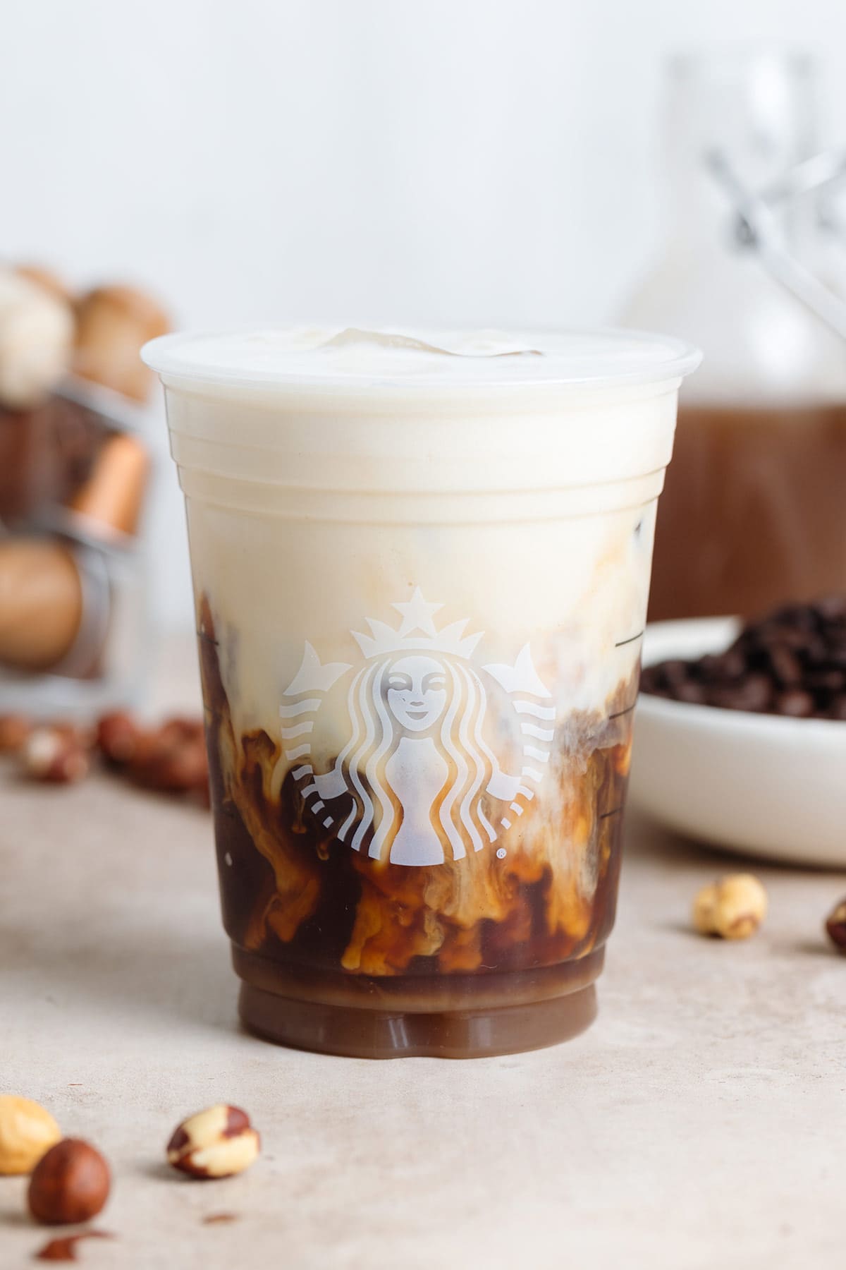 A plastic Starbucks cup with iced latte with frothy milk before mixing the two together.