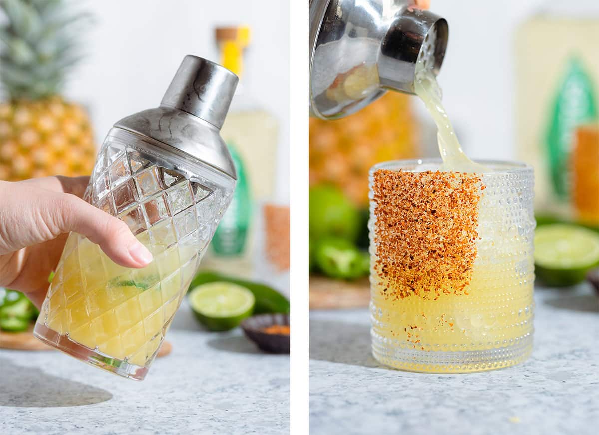 A bright yellow cocktail being shaken in a glass cocktail shaker and being poured into a short glass.