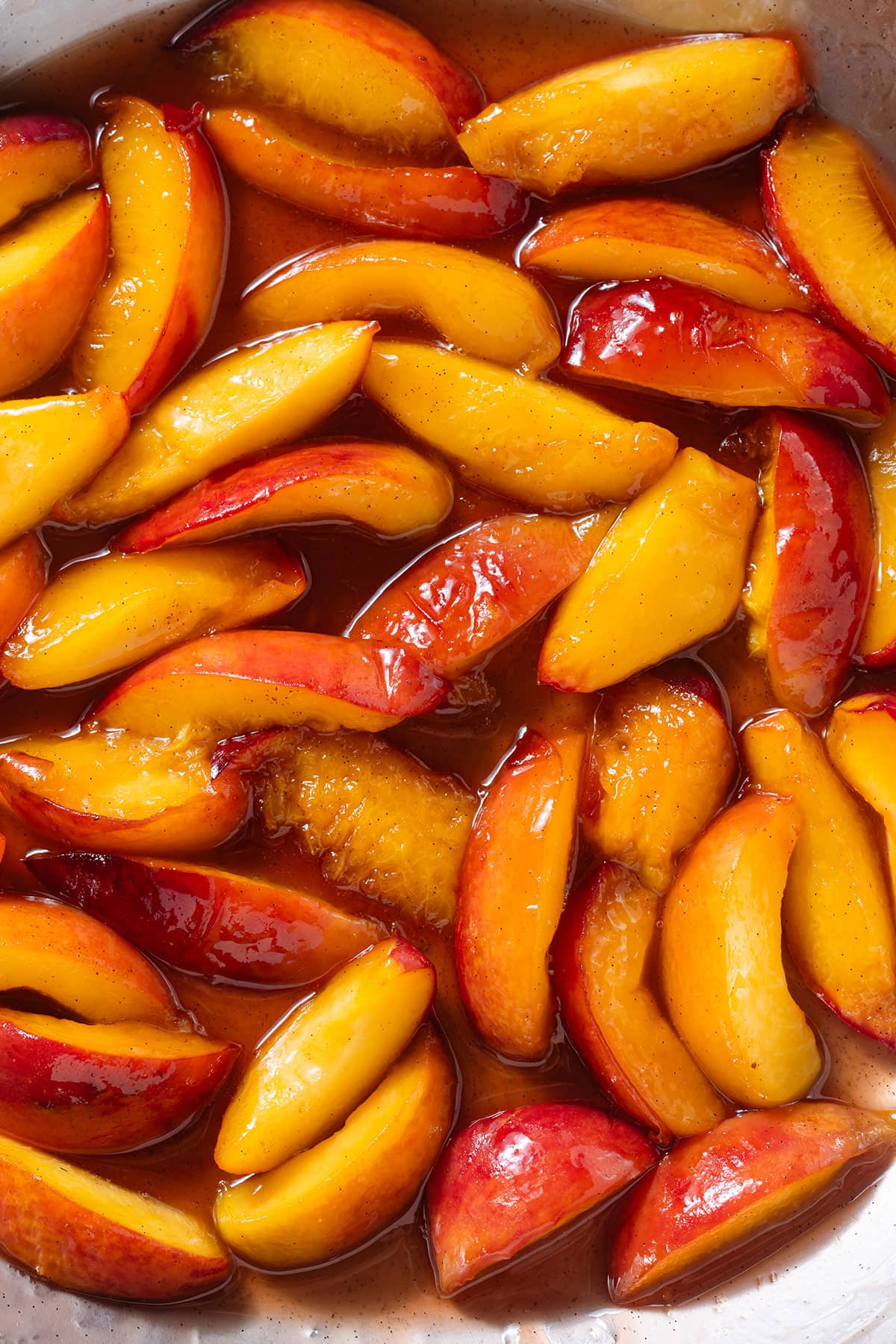 Caramelized peaches in a large steel pan.
