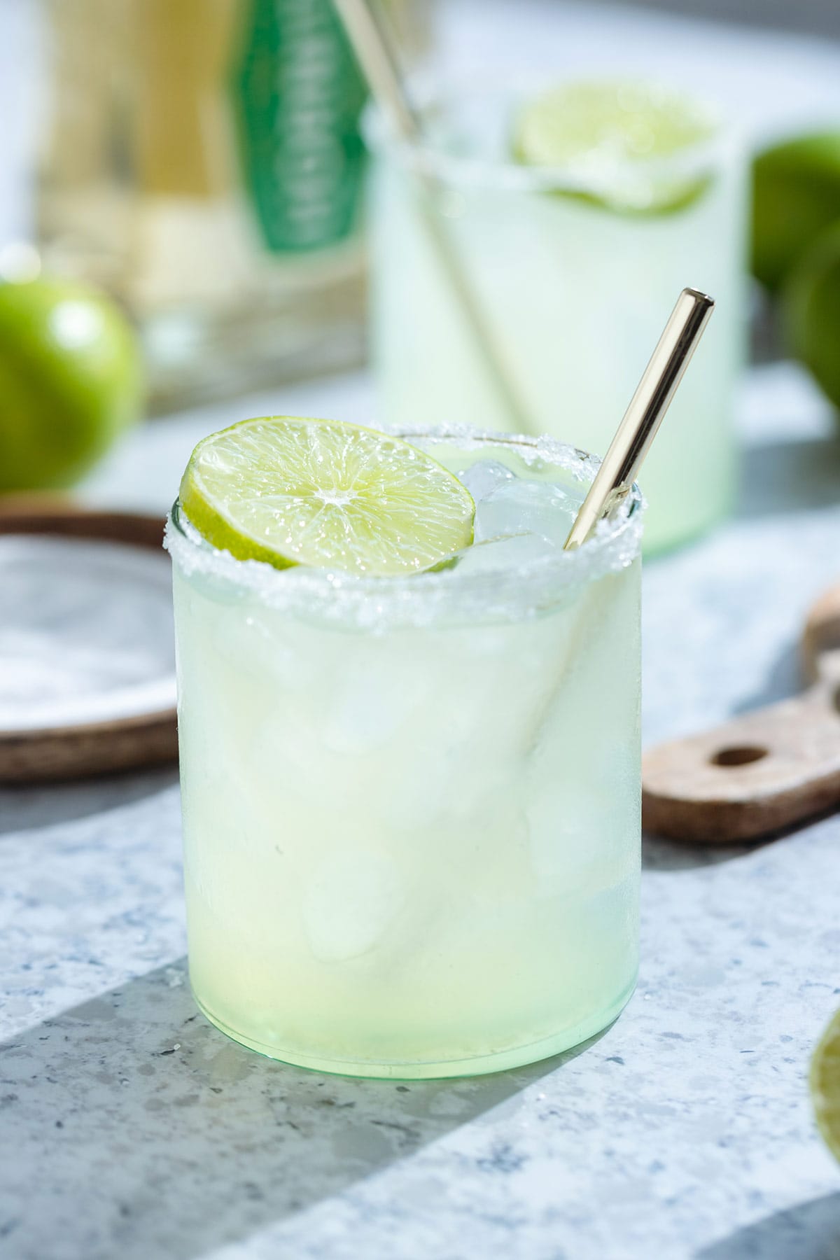 Classic margarita in a short glass with a golden straw garnished a slice of lime.
