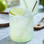 Classic margarita in a short glass with a golden straw garnished a slice of lime.