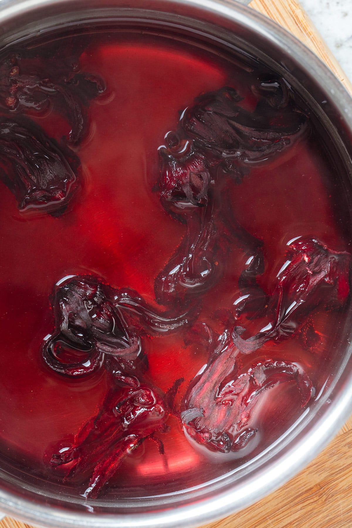 Dried hibiscus flowers steeping in a small pot of water.