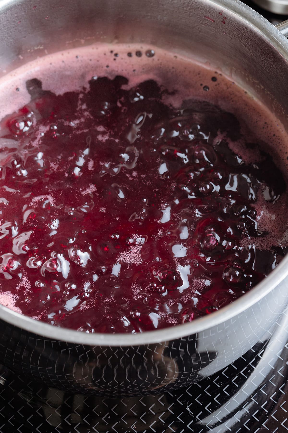 Hibiscus tea simmering with sugar in a small saucepan.