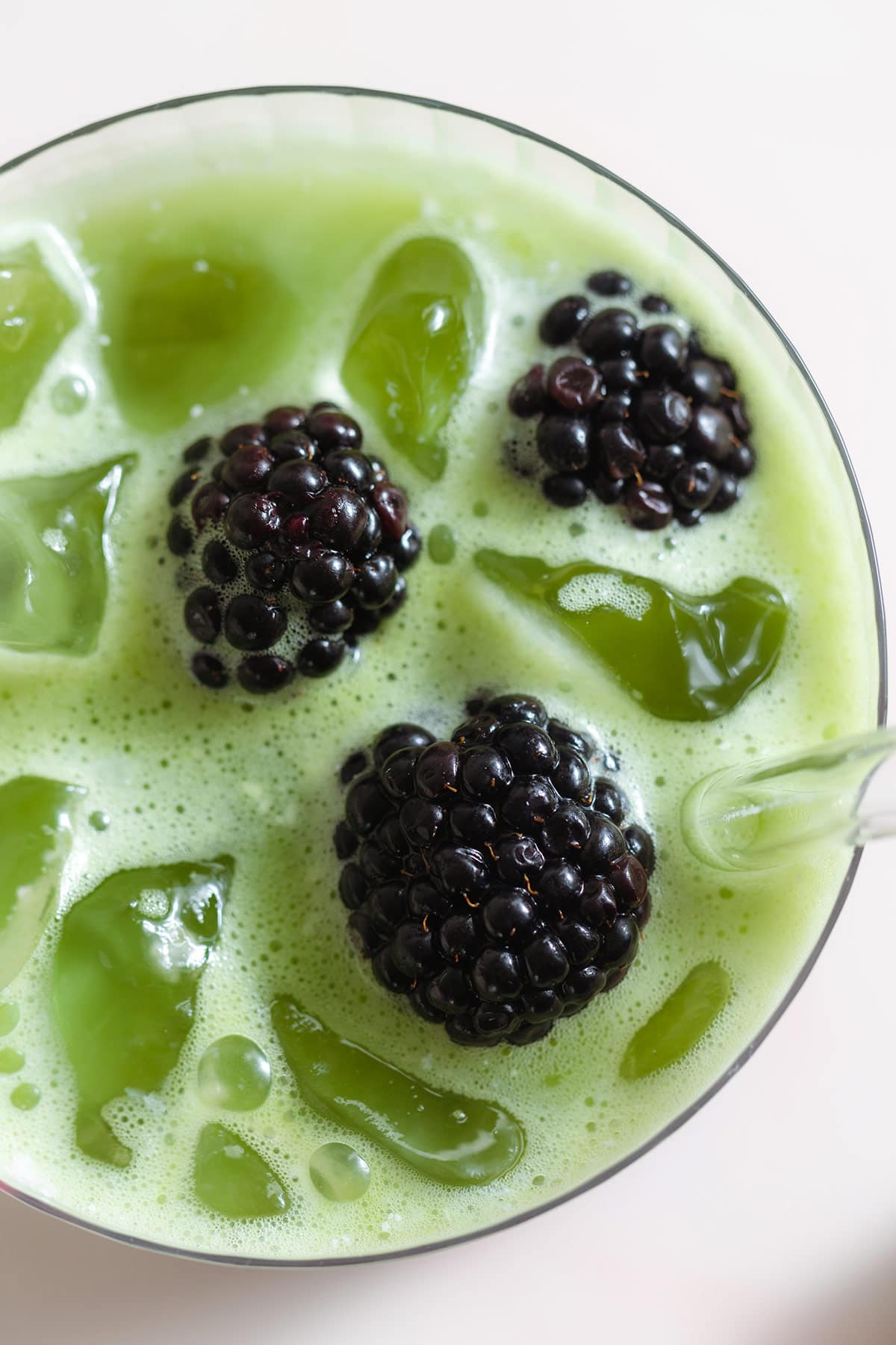 Iced matcha latte in a glass garnished with fresh blackberries.