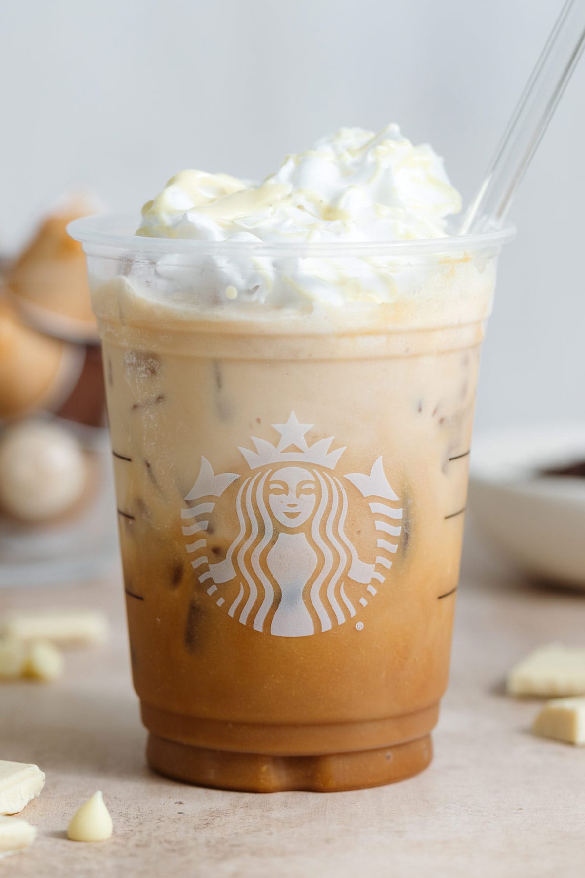 A plastic Starbucks cup with iced mocha over ice garnished with whipped cream and melted white chocolate.
