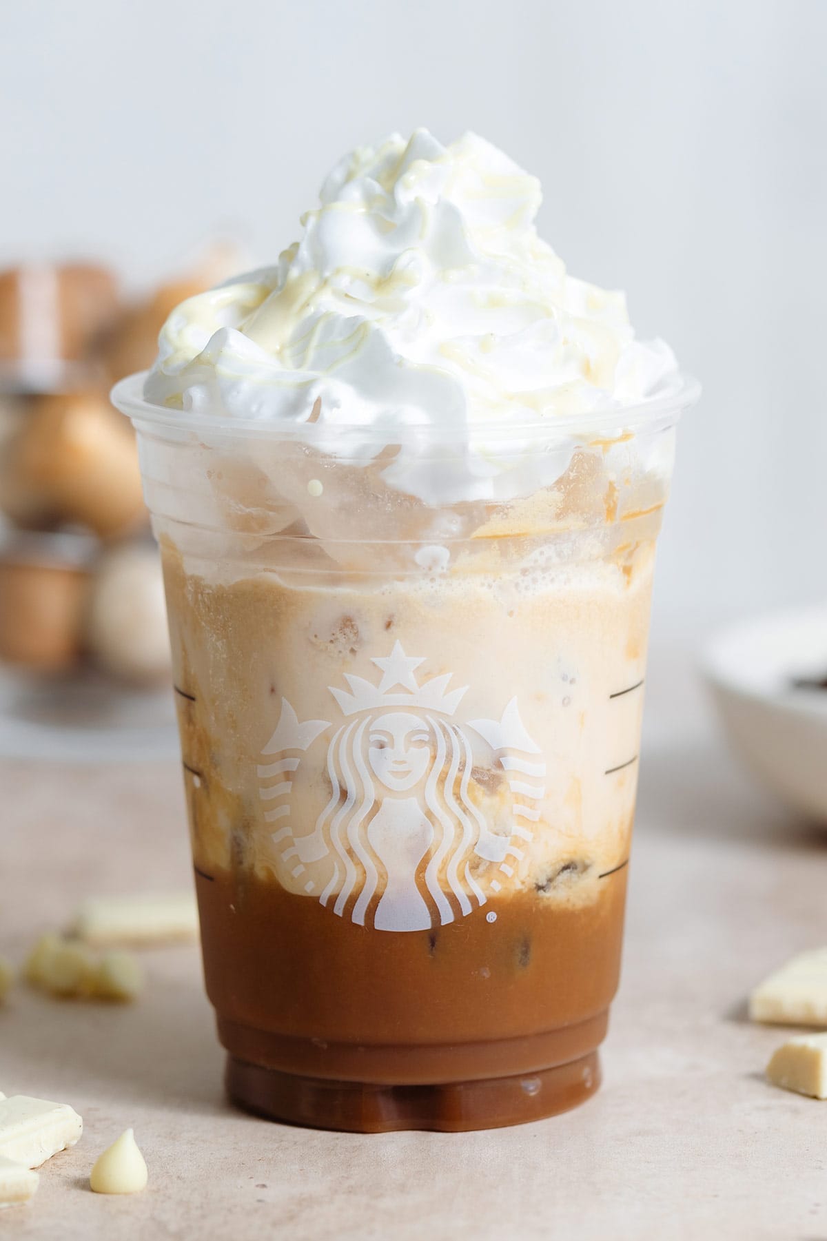 A plastic Starbucks cup with iced mocha over ice garnished with whipped cream and melted white chocolate.